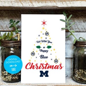 Puede incluir: Tarjeta de Navidad blanca con un diseño festivo. La tarjeta presenta una forma de árbol de Navidad hecha de estrellas y adornos, con el texto "We Wish You a Happy Blue Christmas" en rojo y azul. La tarjeta también tiene la letra "M" en azul.