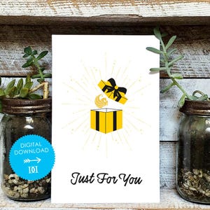 May include: A white card with a yellow and black gift box illustration, a black bow, and the text "Just For You." A blue circle with "DIGITAL DOWNLOAD" is on the left. The card is displayed in front of a rustic wooden background.