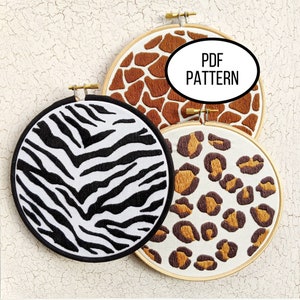 May include: Three embroidery hoops featuring different animal print designs: zebra, giraffe and leopard. The hoops are made of wood and have a natural finish. The text "PDF PATTERN" is visible in the image.