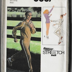 May include: Simplicity 8887 sewing pattern envelope. The cover features a woman in a tan tracksuit with white stripes, and illustrations of athletic wear. The text "Time Saver Stretch Knit" is also visible.