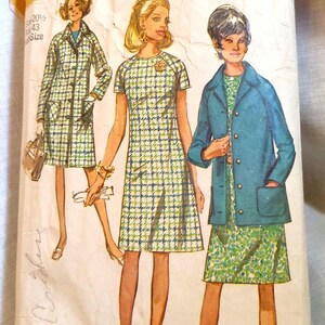 May include: A white ceramic mug with a black handle and the text "But First, Coffee" in a bold, black font. The mug is set against a blurred background, suggesting a cozy setting.