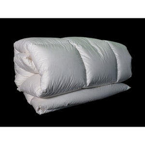 May include: A white down comforter folded in half, showing the stitching and filling. The comforter is made of soft, breathable fabric and is designed to provide warmth and comfort.