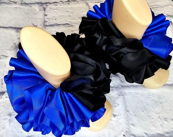 May include: A pair of blue and black ruffled ankle cuffs. The cuffs are made of satin ribbon and are tied with a bow.