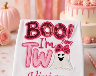 May include: A white t-shirt featuring an embroidered design with the text "BOO! I'm Two" in pink and glittery dark pink. Below the text is a white ghost character wearing a pink glittery bow, and the name "Vivian" in pink cursive script.