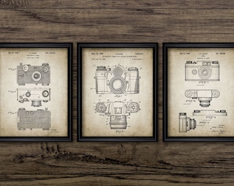 May include: Three vintage camera patent drawings in black and white. The drawings show different angles of the cameras and their components. The patent numbers and dates are included in the drawings.