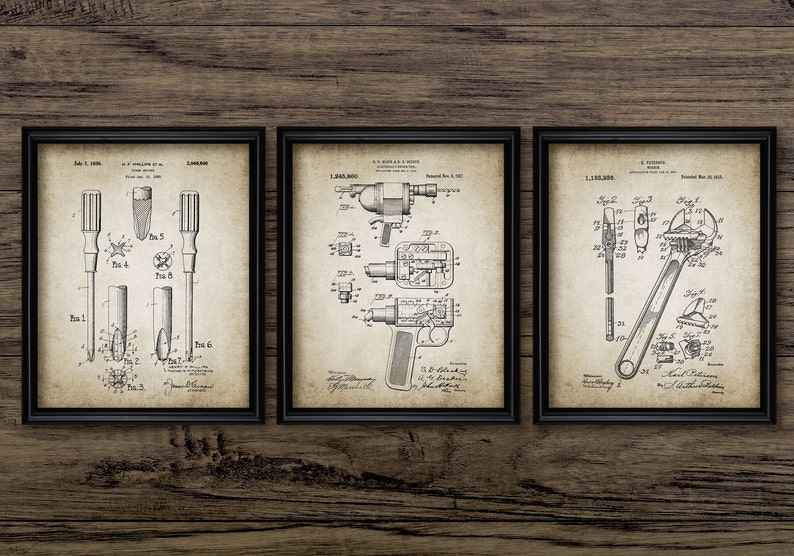 May include: Three vintage patent drawings in black and white, framed in black frames. The drawings depict a screwdriver, a drill, and a wrench. The drawings are on a light brown wood background.