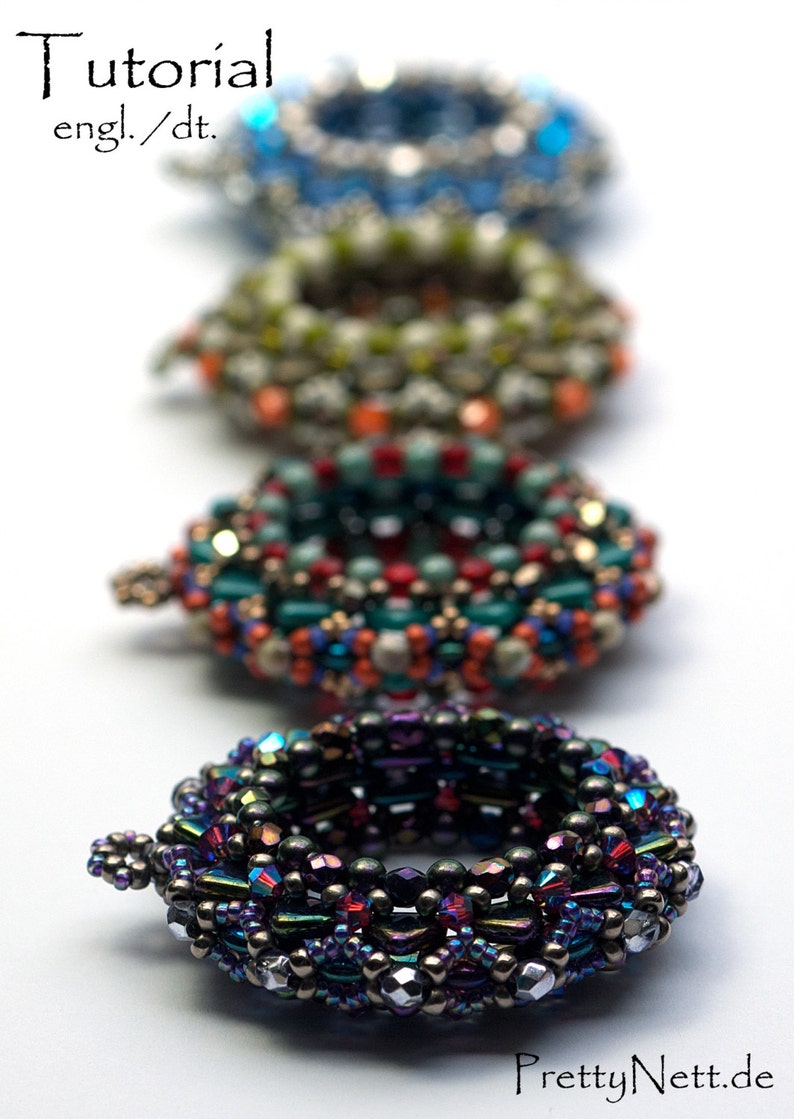 May include: Five beaded rings in various colors and patterns, including blue, green, red, and purple. The rings are stacked on top of each other, with the largest ring at the bottom and the smallest ring at the top. The rings are made of small beads that are woven together in intricate designs.