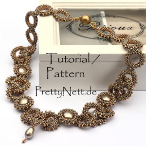 Może przedstawiać: Złoty i szary naszyjnik z perełką. Naszyjnik wykonany jest z małych koralik&oacute;w i ma delikatny, skomplikowany wz&oacute;r. Naszyjnik jest prezentowany w białym pudełku z tekstem "Tutorial/Wz&oacute;r PrettyNett.de".