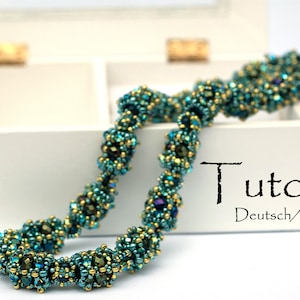 Könnte beinhalten: Eine türkisfarbene und goldene Perlenkette mit einem Tutorial auf Deutsch und Englisch. Die Kette besteht aus kleinen Perlen und ist spiralförmig angeordnet.