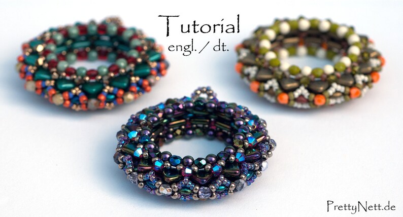 May include: Three beaded rings, one in shades of green, orange, and red, one in shades of brown, orange, and white, and one in shades of purple, blue, and silver. The rings are all about 2 inches in diameter and are made with small seed beads.