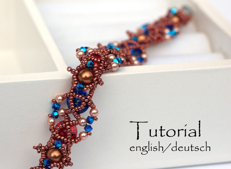 May include: A close-up of a beaded bracelet with a copper, blue and red colour scheme. The bracelet is made with small seed beads and larger round beads. The bracelet is lying on a white surface. The text "Tutorial english/deutsch" is visible in the image.