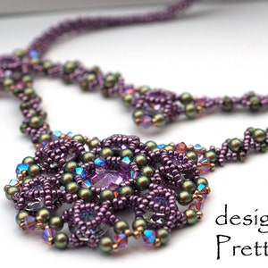 Könnte beinhalten: Eine violette und grüne Perlenkette mit einem großen, kunstvollen Anhänger. Der Anhänger besteht aus kleinen Perlen und Kristallen in verschiedenen Formen und Größen. Die Kette wurde von PrettyNett.de entworfen.