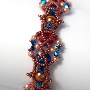 May include: A copper-toned beaded bracelet with a geometric design. The bracelet features blue, red, and cream-coloured beads.