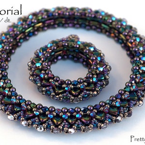 May include: Two iridescent beaded necklaces, one larger than the other, with a purple, blue, and green color scheme. The necklaces are made of small, faceted beads and are arranged in a spiral pattern.