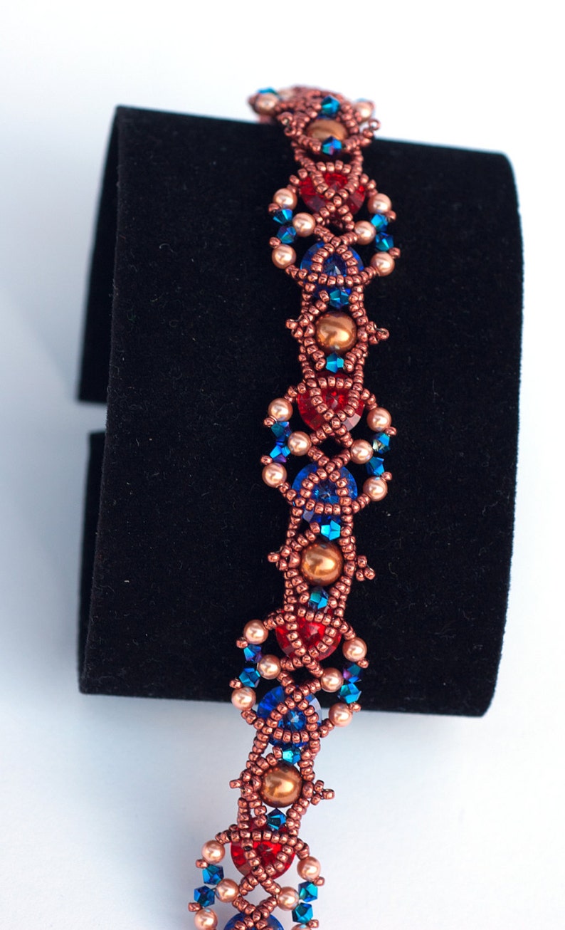 May include: A beaded bracelet with a copper wire design. The bracelet features red, blue, and gold beads in a geometric pattern.