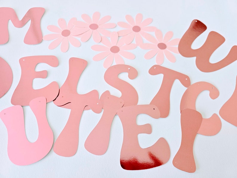 May include: Pink and white paper letters spelling out the word "Welcome" with pink paper flowers.