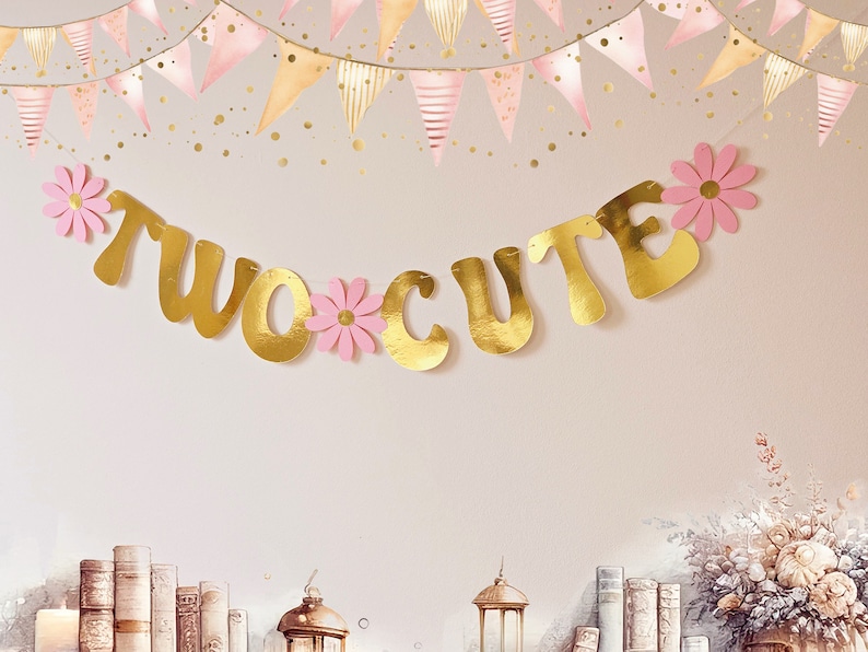 May include: Gold foil banner with the words "TWO CUTE" in a cursive font. The banner is decorated with pink paper flowers.