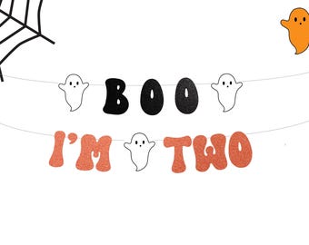 May include: A Halloween-themed banner with the words "BOO I'M TWO" in black and orange glitter lettering. The banner includes ghost and spiderweb illustrations, perfect for a second birthday celebration.