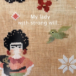 Pode incluir: Bordado de ponto cruz com uma mulher de cabelo escuro segurando um pequeno macaco. O fundo inclui uma borboleta, flores e um pássaro. O texto "My lady with strong will..." é bordado em fio branco.