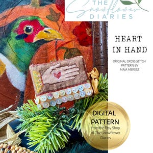 May include: A digital cross-stitch pattern titled "Heart in Hand" by Maja Merész. The image features a detailed cross-stitch design of a hand holding a heart, adorned with sequins. The background includes a pheasant painting and floral elements.