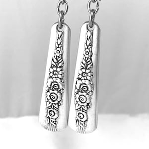 May include: Silver earrings with a floral design. The earrings are made from repurposed silverware and have a delicate, vintage look.
