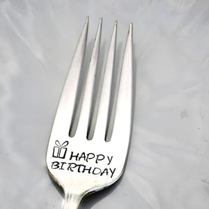 May include: A silver fork with the words "Happy Birthday" and a small gift box design engraved on the handle.