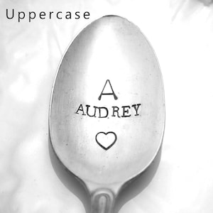 May include: A silver spoon with the letter "A" and the name "Audrey" engraved on it. A small heart is engraved below the name.