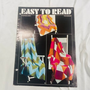 May include: A vintage knitting pattern booklet titled "Easy to Read" featuring three colourful knitted blankets draped over white chairs. The blankets showcase chevron and geometric patterns in shades of blue, green, orange, pink, and yellow.