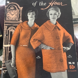 Puede incluir: Una portada de revista vintage con dos mujeres que llevan suéteres de punto naranja. La revista se titula "Hand Knit Fashions of the Hour" y es para Bear Brand Fleisher Yarns. La portada también presenta un reloj y el texto "Vol. 59 60¢ (En Canadá 80¢)"