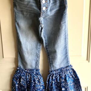 May include: A white ceramic mug with a black handle and the text "But First, Coffee" in a bold, black font. The mug is set against a blurred background, suggesting a cozy setting.