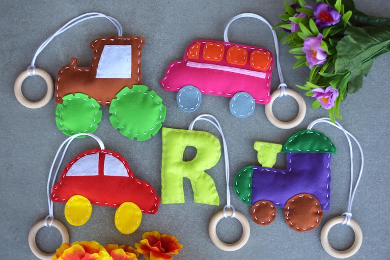 Puede incluir: Un conjunto de seis juguetes de fieltro para beb&eacute;s y ni&ntilde;os peque&ntilde;os. Los juguetes tienen forma de tractor, autob&uacute;s, coche, tren y la letra R. Cada juguete tiene un anillo de madera unido a &eacute;l.