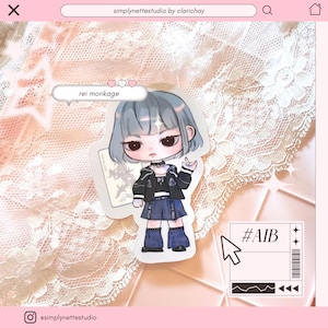 May include: A die-cut sticker featuring a stylized anime-inspired character with short grey hair, wearing a black jacket over a dark top, a blue skirt, and dark boots. A speech bubble above the character reads "rei morikage" with three hearts.