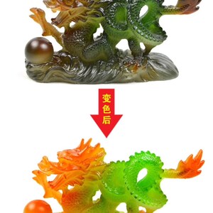 May include: A green and orange dragon figurine with a pearl in its paw. The dragon is curled up on a base that looks like a wave. The figurine is made of glass and has a shiny finish.