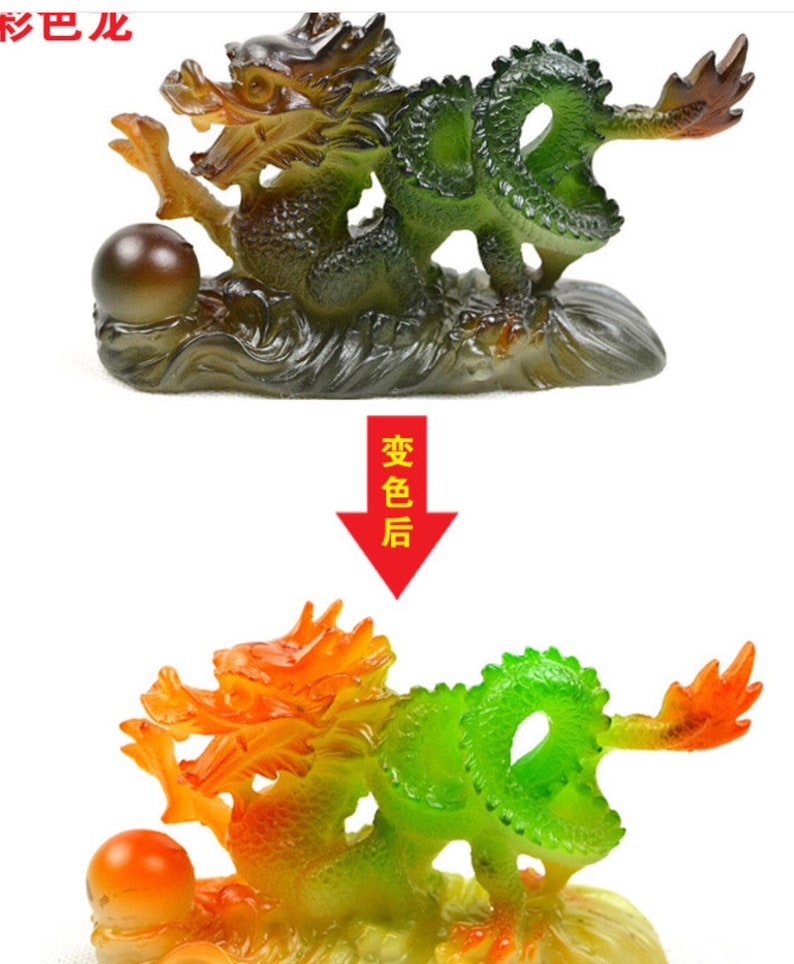 May include: A green and orange dragon figurine with a pearl in its paw. The dragon is curled up on a base that looks like a wave. The figurine is made of glass and has a shiny finish.