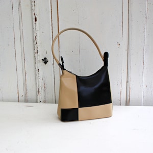 May include: A black and beige checkered handbag with a short handle.
