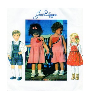 May include: A sewing pattern for children's clothing featuring three different designs. The pattern includes a plaid overall outfit, a pink gingham dress with a strawberry applique, and a red gingham dress with a watermelon applique. The pattern is titled "Jan Briggs".