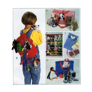 May include: A child wearing overalls is carrying a red backpack with stuffed animals. The backpack has a drawstring closure and is decorated with a green and yellow striped fabric. The child is also carrying a stuffed animal in their right hand. The image shows several other stuffed animal storage options, including a red and white gingham tote bag, a blue tote bag, and a wall-mounted storage rack.