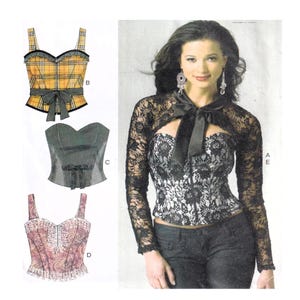 May include: The image shows three corset tops and a woman wearing a lace bolero over a corset. The tops include a yellow plaid corset with a black bow, a grey corset with a bow, and a pink paisley corset with a zip. The woman wears a black lace bolero.