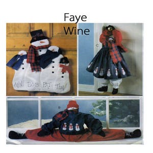 Op de afbeelding: Een collage van decoraties met sneeuwmannen. Eén is een deurhanger met drie sneeuwmannen en namen. Een andere is een sneeuwman in een jurk. De laatste is een sneeuwman in een splitpositie. De tekst "Faye Wine" staat bovenaan.