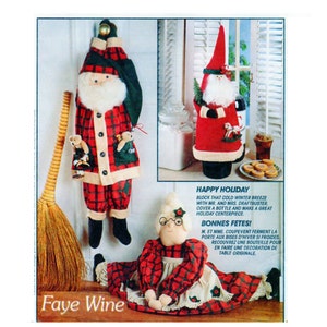 Op de afbeelding: Een feestelijke vakantiedisplay met stoffen kerstman- en mevrouw Claus-fleshoezen en een tochtstopper. De kerstmanfiguur is gekleed in een rood geruit outfit met een witte baard. De mevrouw Claus-figuur draagt een rood geruite jurk.