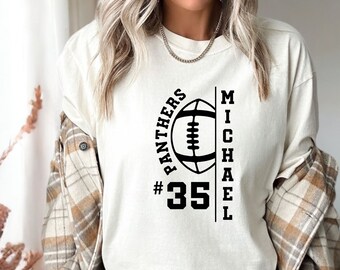 Könnte beinhalten: Weißes Langarm-T-Shirt mit einem schwarzen Football-Motiv und dem Text "Panthers #35 Michael" auf der Vorderseite.