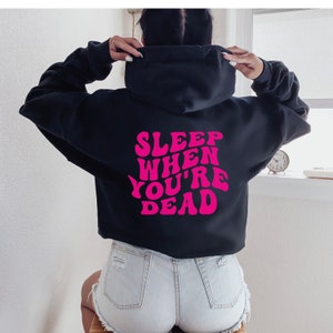 May include: Black cropped hoodie with a pink graphic that says "SLEEP WHEN YOU'RE DEAD" in a retro font.