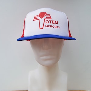 Puede incluir: Una gorra de camionero blanca, azul y roja con un logotipo rojo que dice "OTEM MERCURY" en la parte delantera.