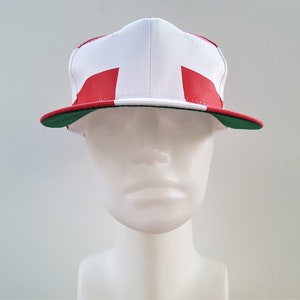 May include: A white, red and green baseball cap with a flat brim. The cap is designed with a red and white stripe pattern.