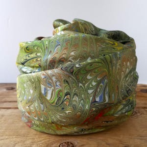 May include: A white ceramic mug with a black handle and the text "But First, Coffee" in a handwritten style. The mug is on a white surface. The mug is approximately 4 inches tall.