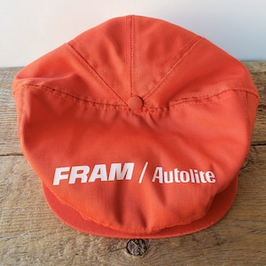 Könnte beinhalten: Orangefarbene Baseballkappe aus Baumwolle mit einem weißen Logo, auf dem "FRAM/Autolite" steht.