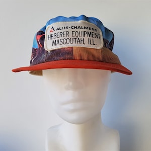 Puede incluir: Una gorra de béisbol roja y azul con un parche blanco que dice "Allis-Chalmers Heberer Equipment Mascoutah, Ill."