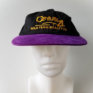 Puede incluir: Gorra de béisbol negra y morada con el logotipo bordado "Century 21 Gold Team Realty Ltd."