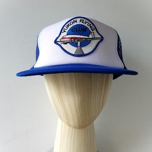 Könnte beinhalten: Eine weiße Keramik-Tasse mit schwarzem Henkel und dem Text "But First, Coffee" in fetter, schwarzer Schrift. Die Tasse steht vor einem neutralen Hintergrund, der ihr schlichtes Design hervorhebt.