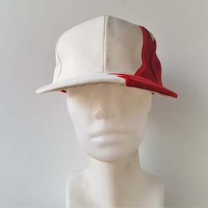 May include: A white and red baseball cap with a curved brim. The cap is two-toned, with a white front panel and a red side panel that extends to the brim. The cap is displayed on a white mannequin head.